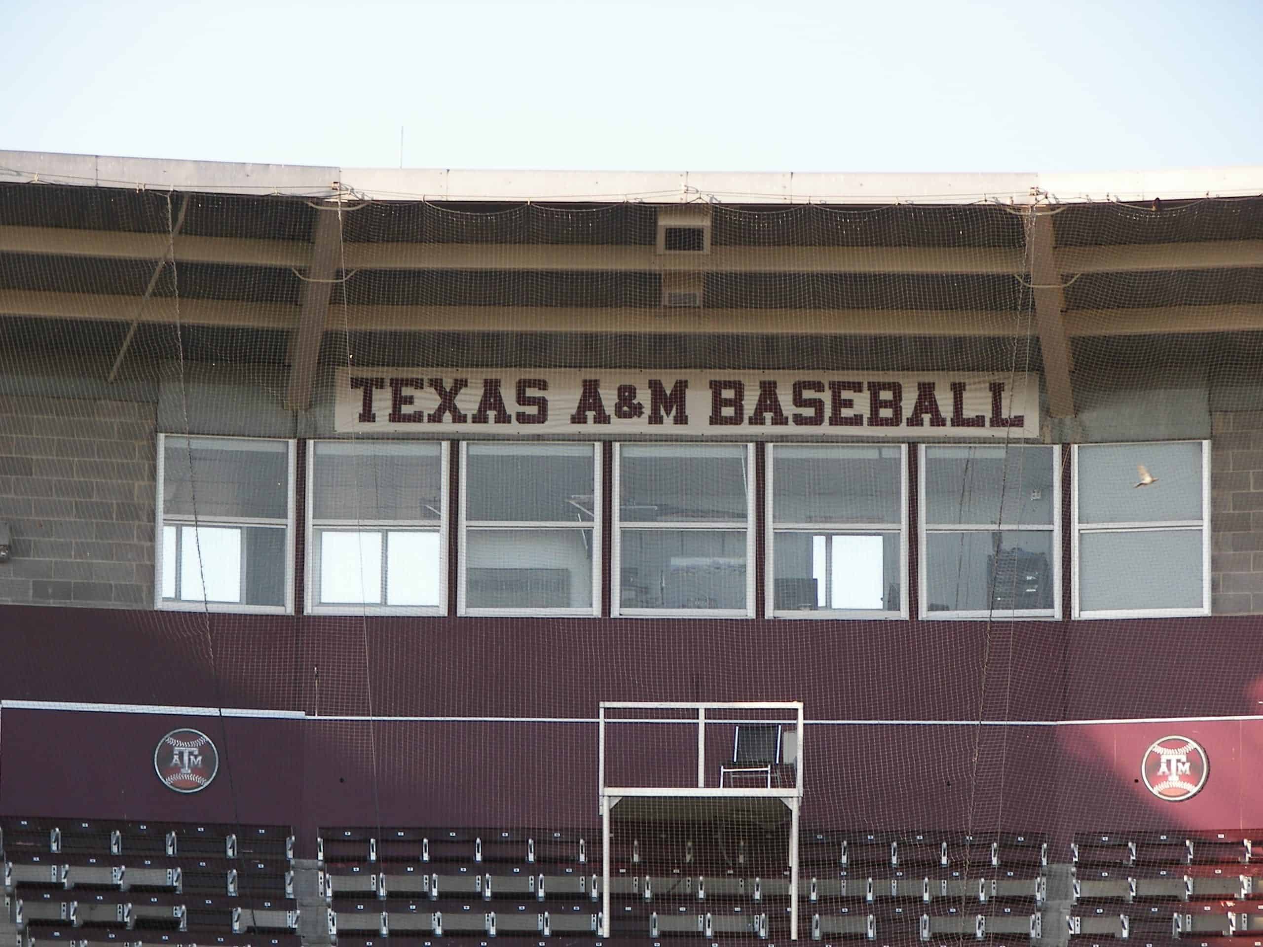Modern baseball stadium with large windows, safety netting, and Texas A&M branding.