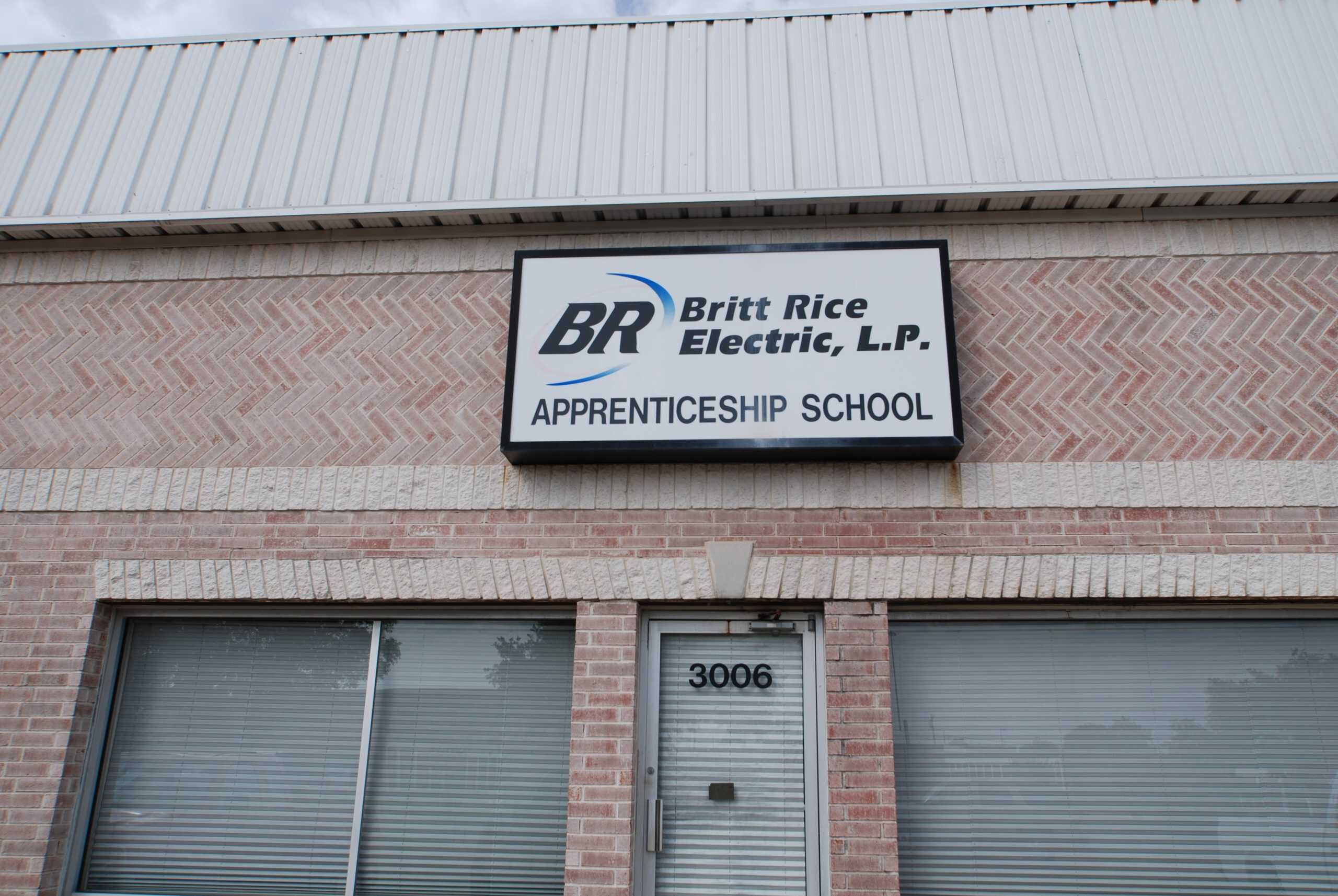Sign for Britt Rice Electric, L.P. apprenticeship school on brick building facade.