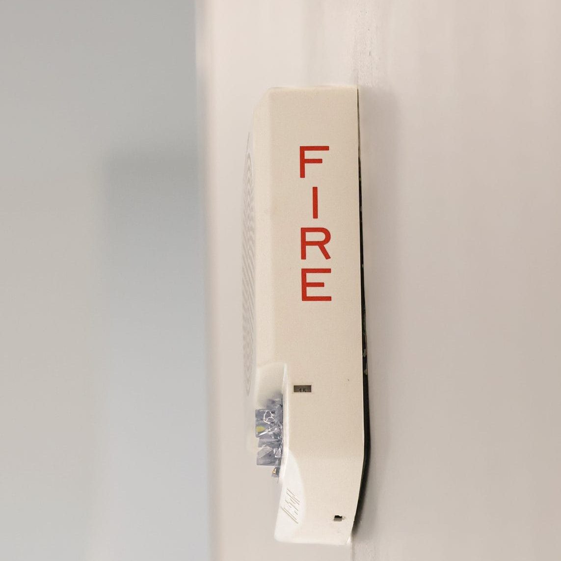 Close-up of a white fire alarm box mounted on a wall, labeled "FIRE" in red letters.