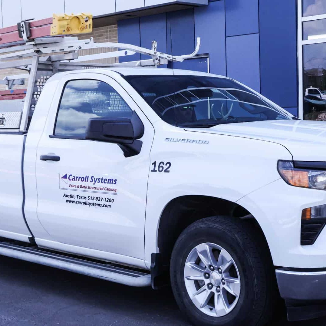 Electrician service vehicle with ladders and tools, branded for Carroll Systems.
